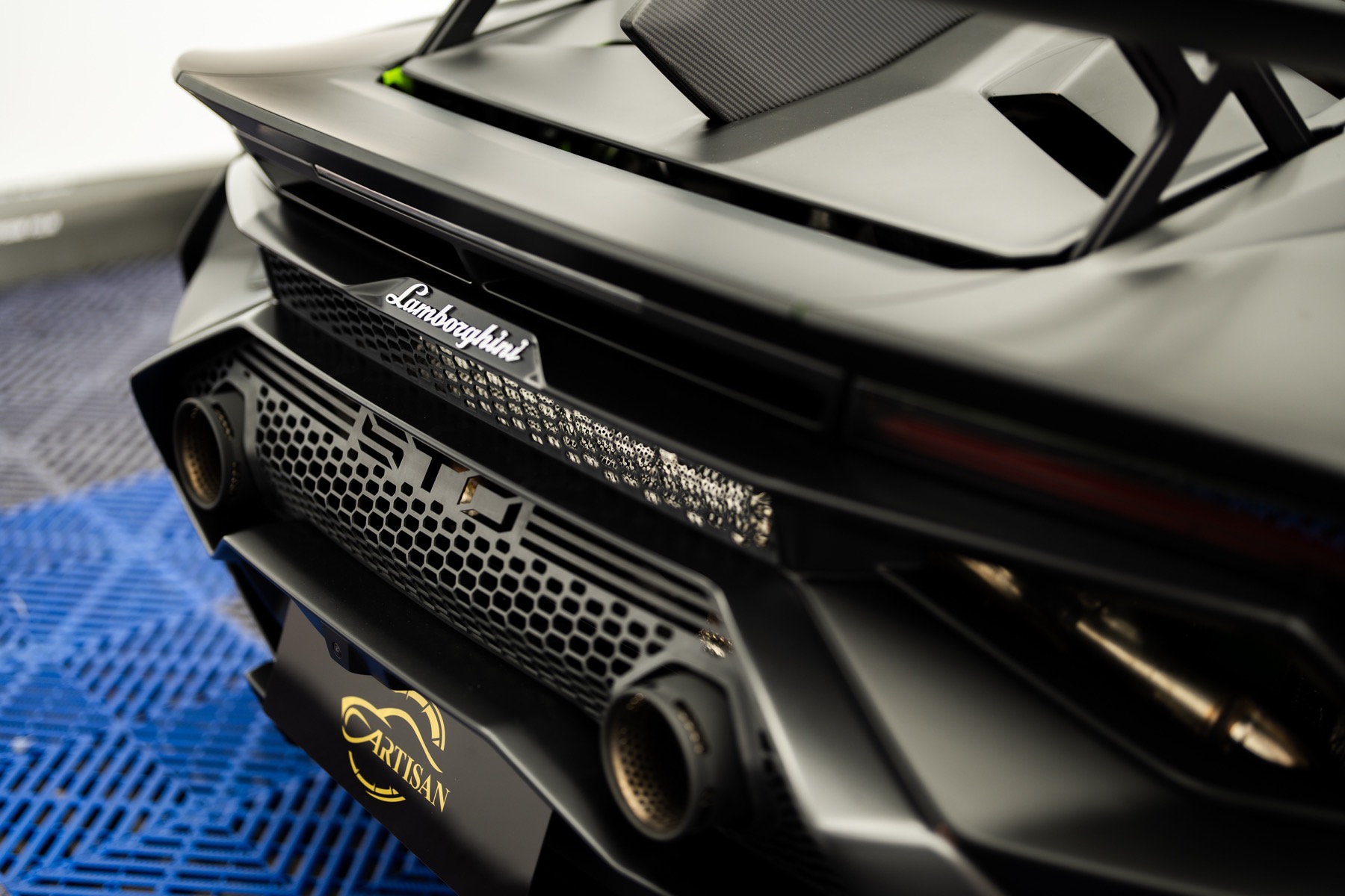 Close-up of a matte black Lamborghini rear detail inside the Artisan workshop