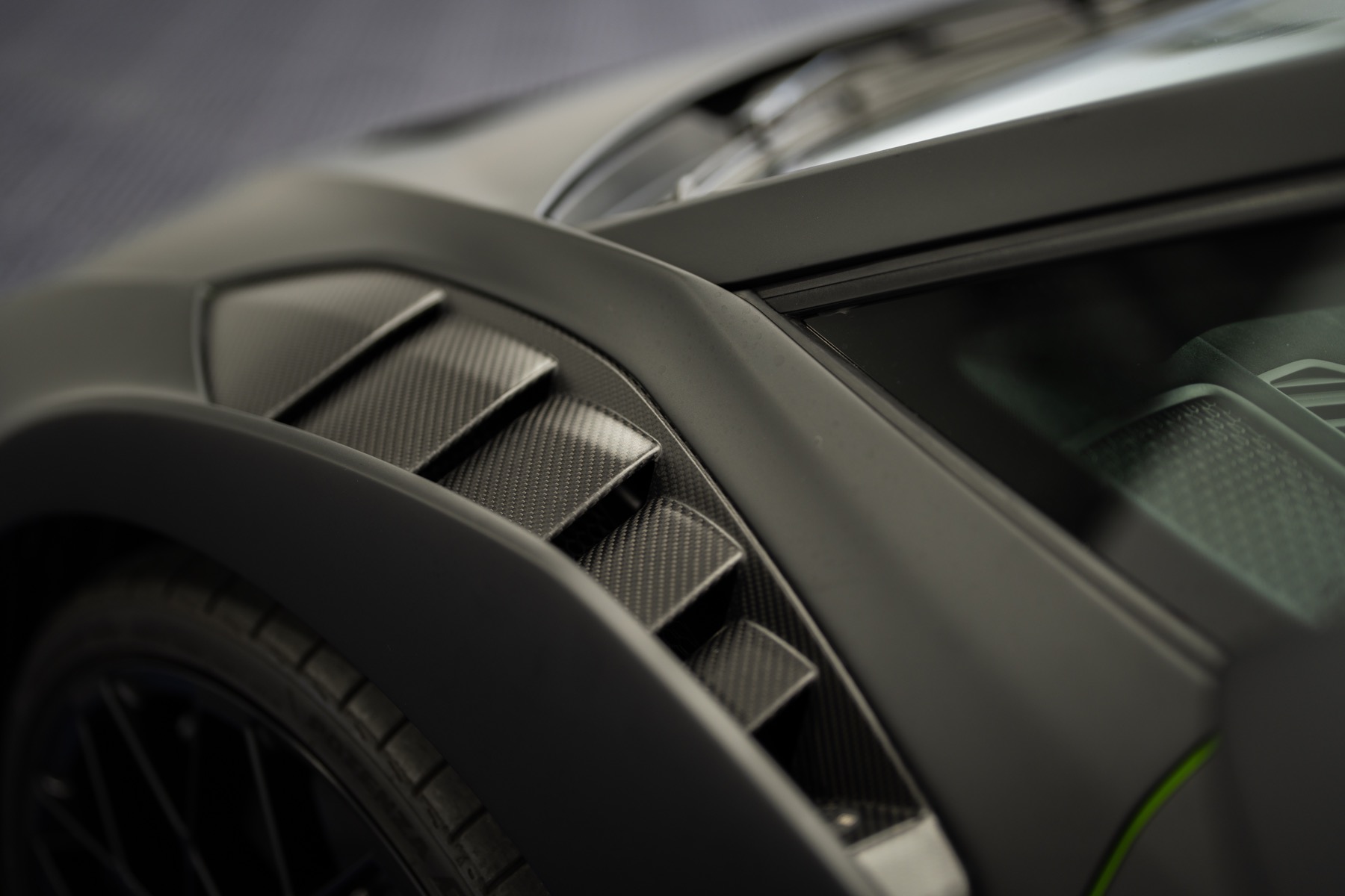 Close-up of a black wide-body front fender and carbon vent detail